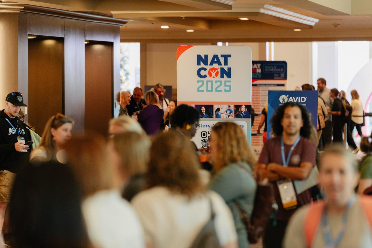 A large group of people at a conference with a sign displaying 'NATCON 2025' in the background. A large group of people at a conference with a sign displaying 'NATCON 2025' in the background.