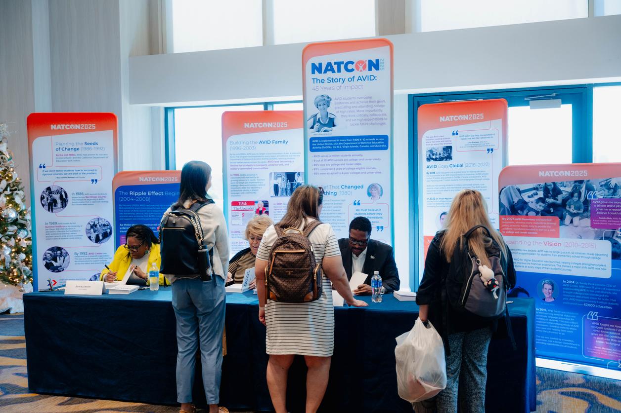 Participants engaging at a NATCON 2025 booth with informational posters in the background. Participants engaging at a NATCON 2025 booth with informational posters in the background.