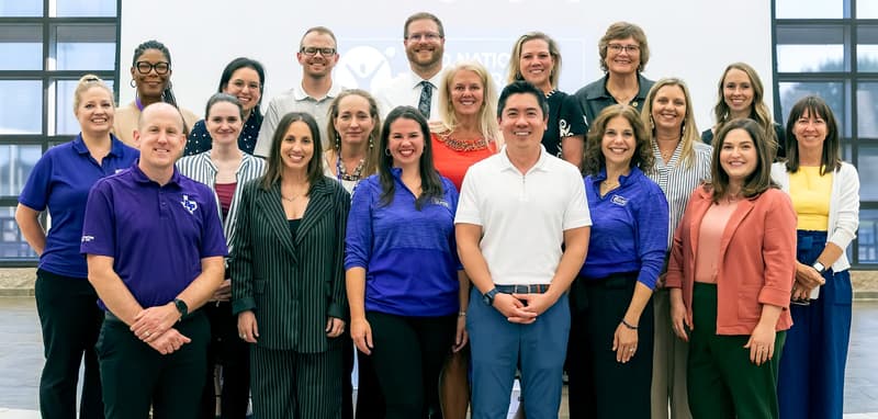 A group of people standing in a room, posing for a photo. A group of people standing in a room, posing for a photo.