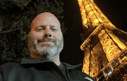 A person in a dark jacket standing in front of the illuminated Eiffel Tower at night. A person in a dark jacket standing in front of the illuminated Eiffel Tower at night.