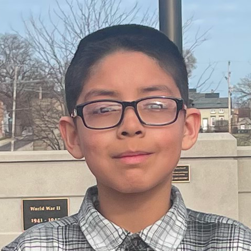 Individual standing outdoors in front of a World War II memorial plaque, wearing a plaid shirt. Individual standing outdoors in front of a World War II memorial plaque, wearing a plaid shirt.