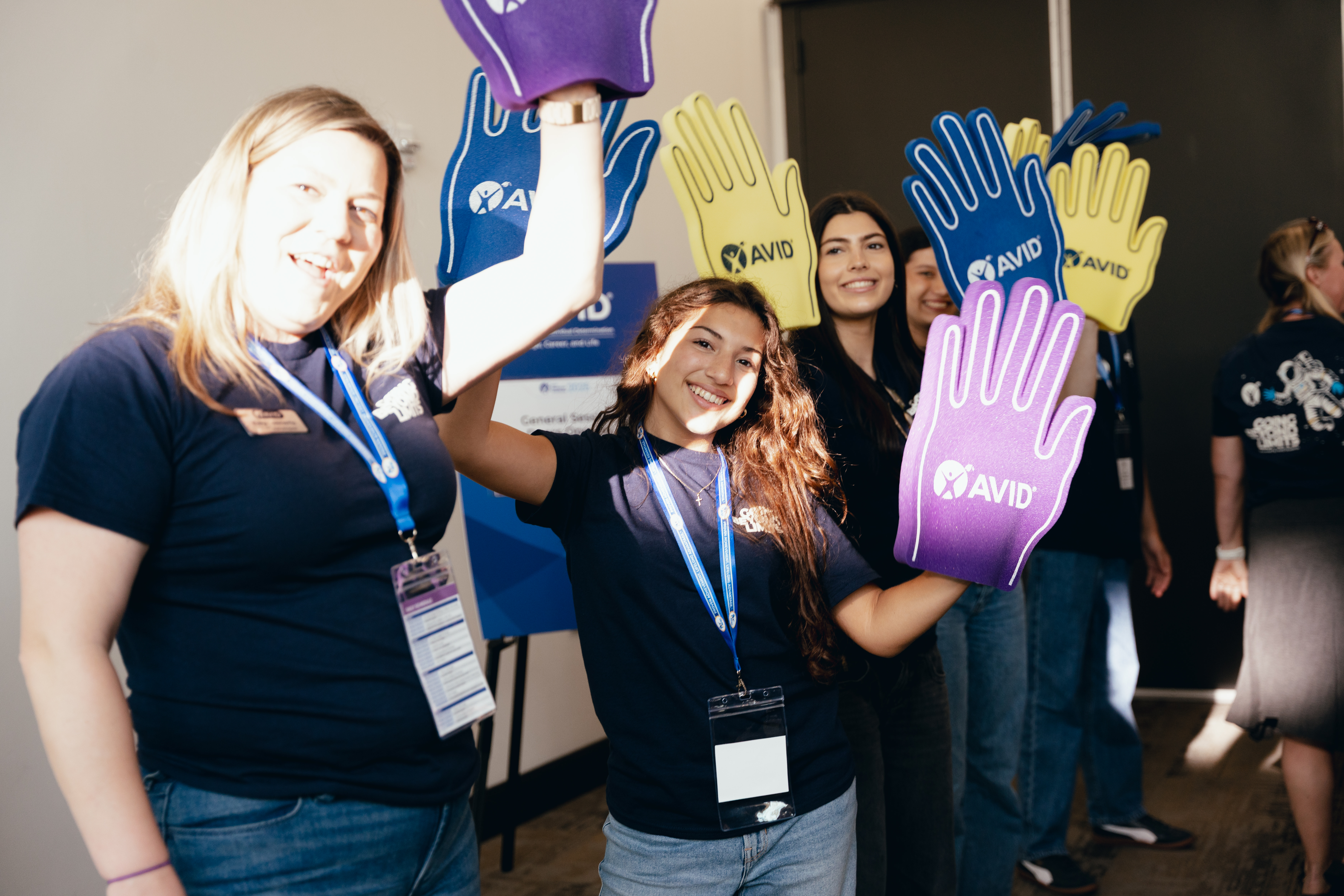 Group of people at an event holding up large colorful foam hands.