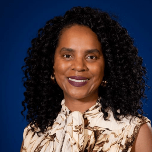 Person with curly hair wearing a patterned scarf, set against a blue background. Person with curly hair wearing a patterned scarf, set against a blue background.