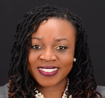 Person with long curly hair and a pearl necklace in a formal attire.