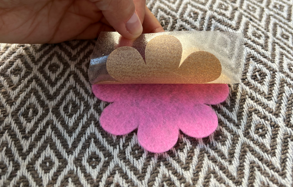 Placing the glitter HTV with the shiny side up on top of the felt layer.