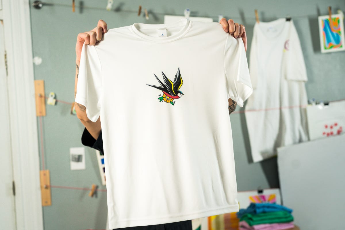 Holding up a white t-shirt with a sublimation marker design.