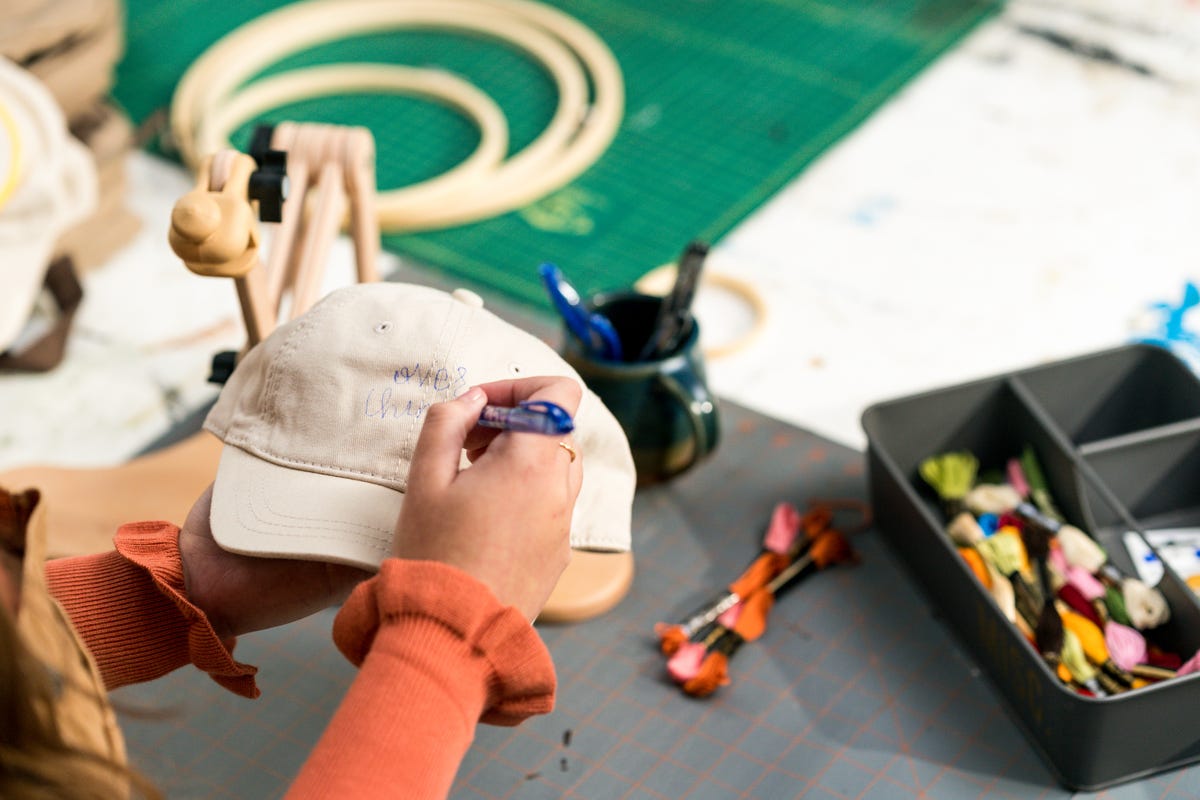 Sophie Nistico sketching her embroidery design "Over thinker" in the front of the cap.