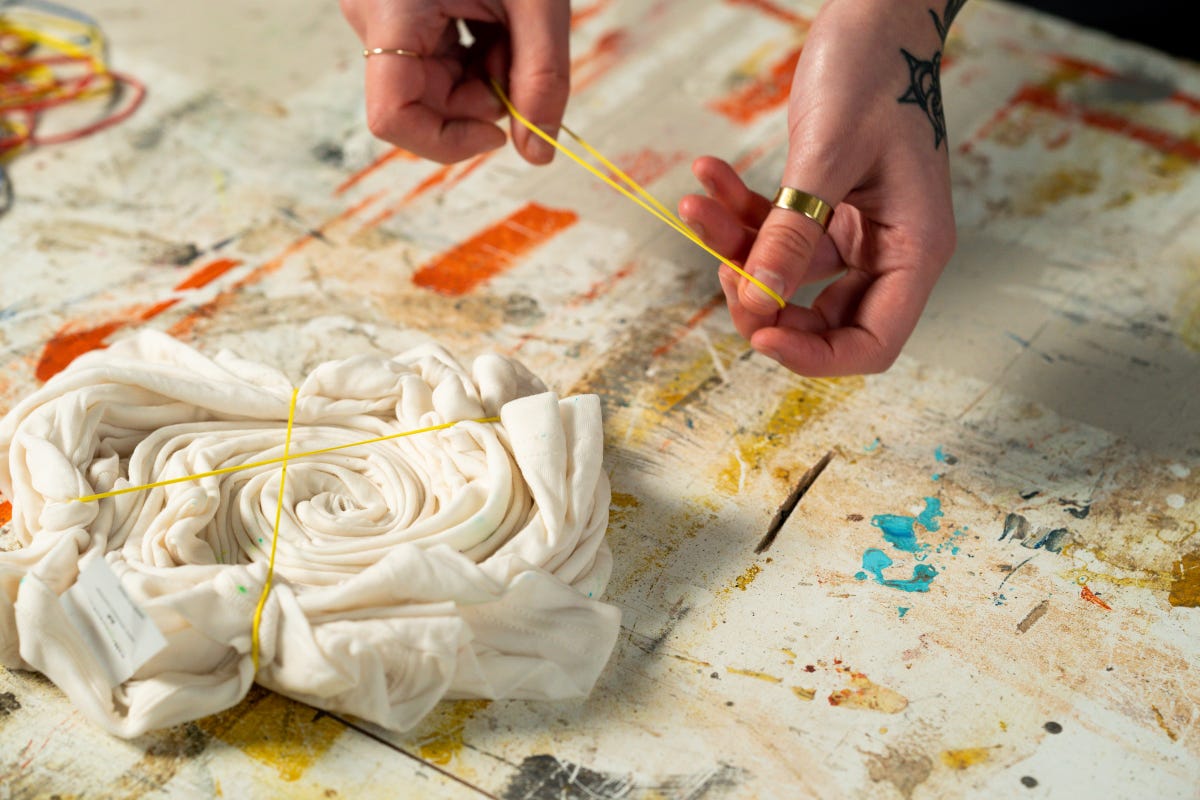 With the white t-shirt folded, start bounding it together with rubber bands.