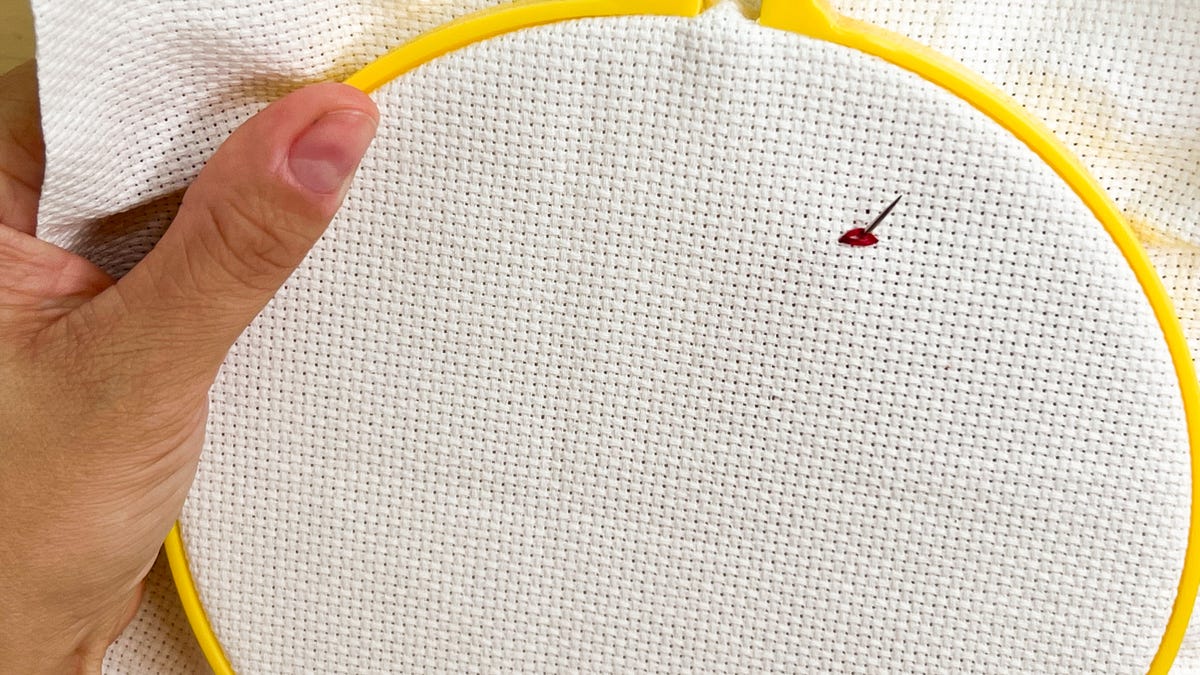 Bringing the needle up through the middle of the first stitch.