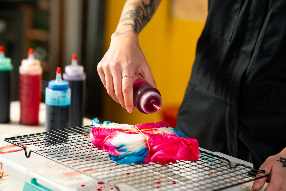Squeezing red dye out of a squeeze bottle and into a white t-shirt.