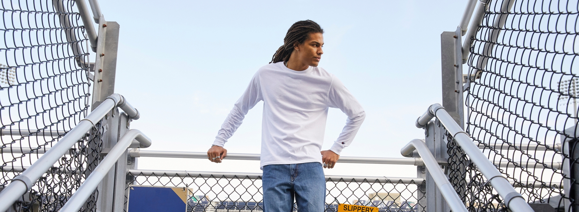 An African American man wearing the Champion Heritage Midweight Jersey Long Sleeve in white looking to the side.