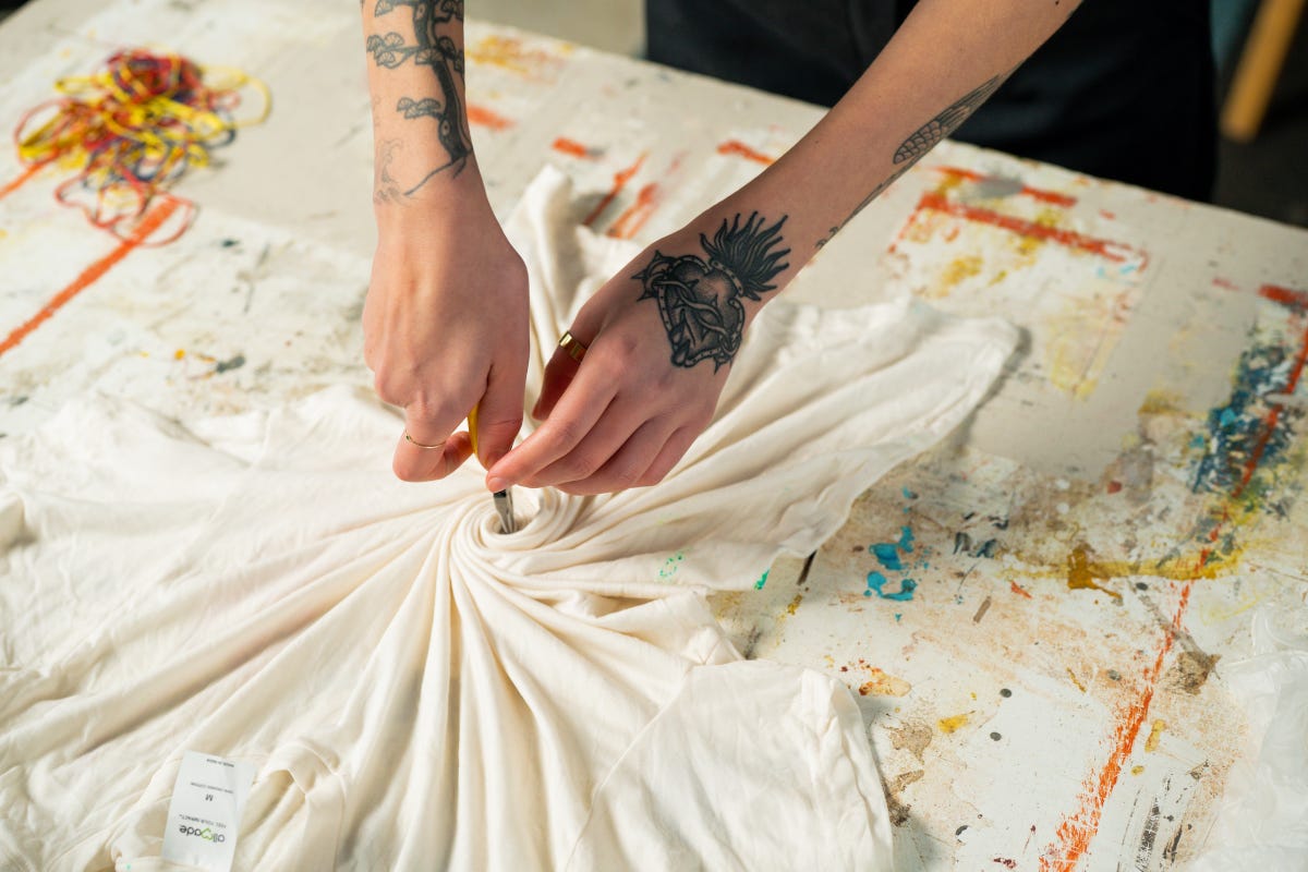 Start folding the t-shirt by pinching the center of the t-shirt using pliers or your fingers.