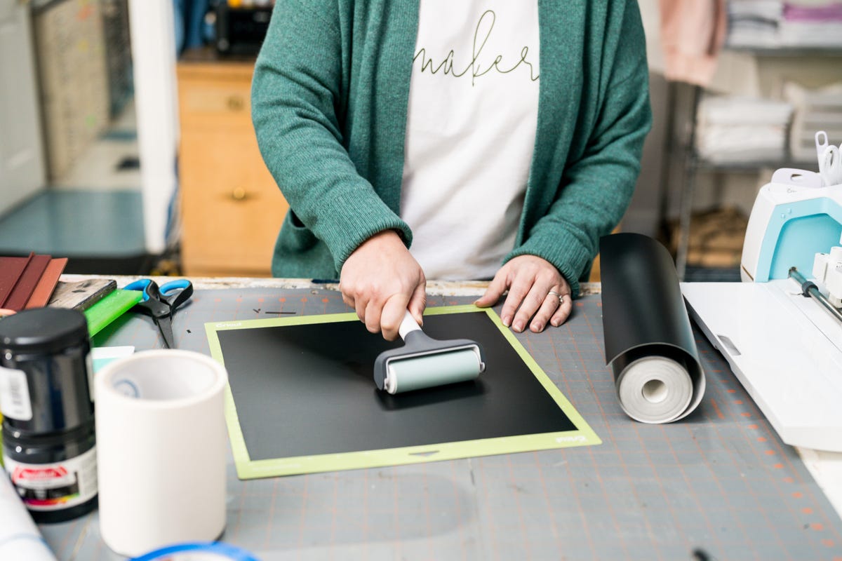 Jennifer using the bayer tool to remove any air bubbles on the vinyl attached to the gripping mat.