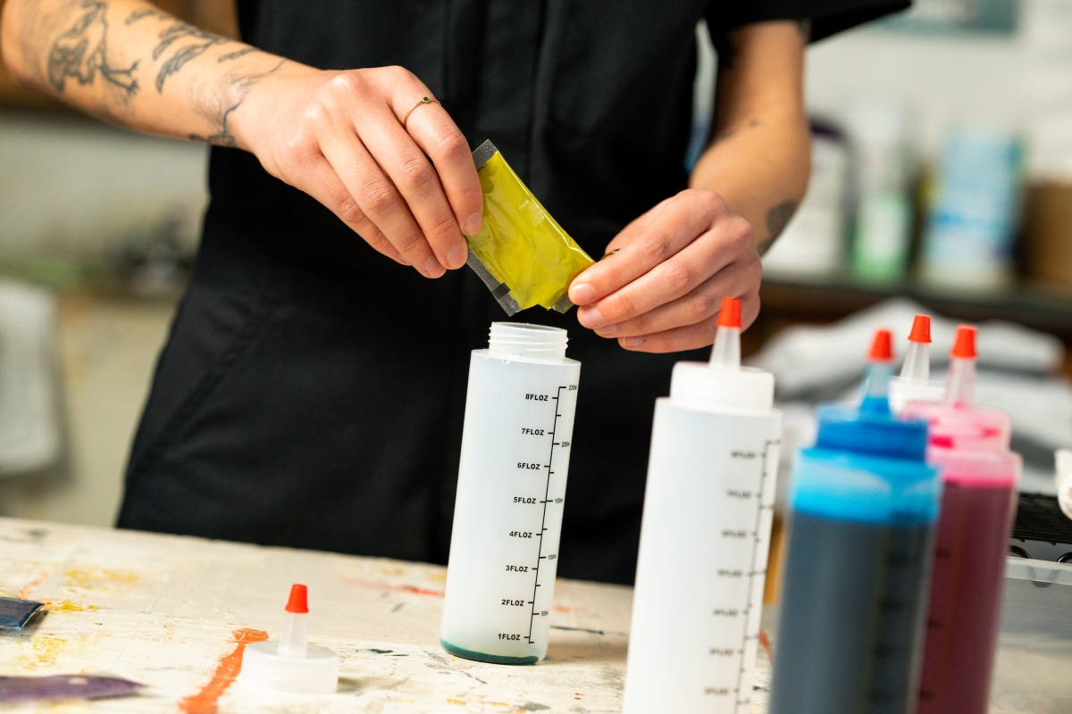 Yellow powdered dye being poured into a squeeze bottle.