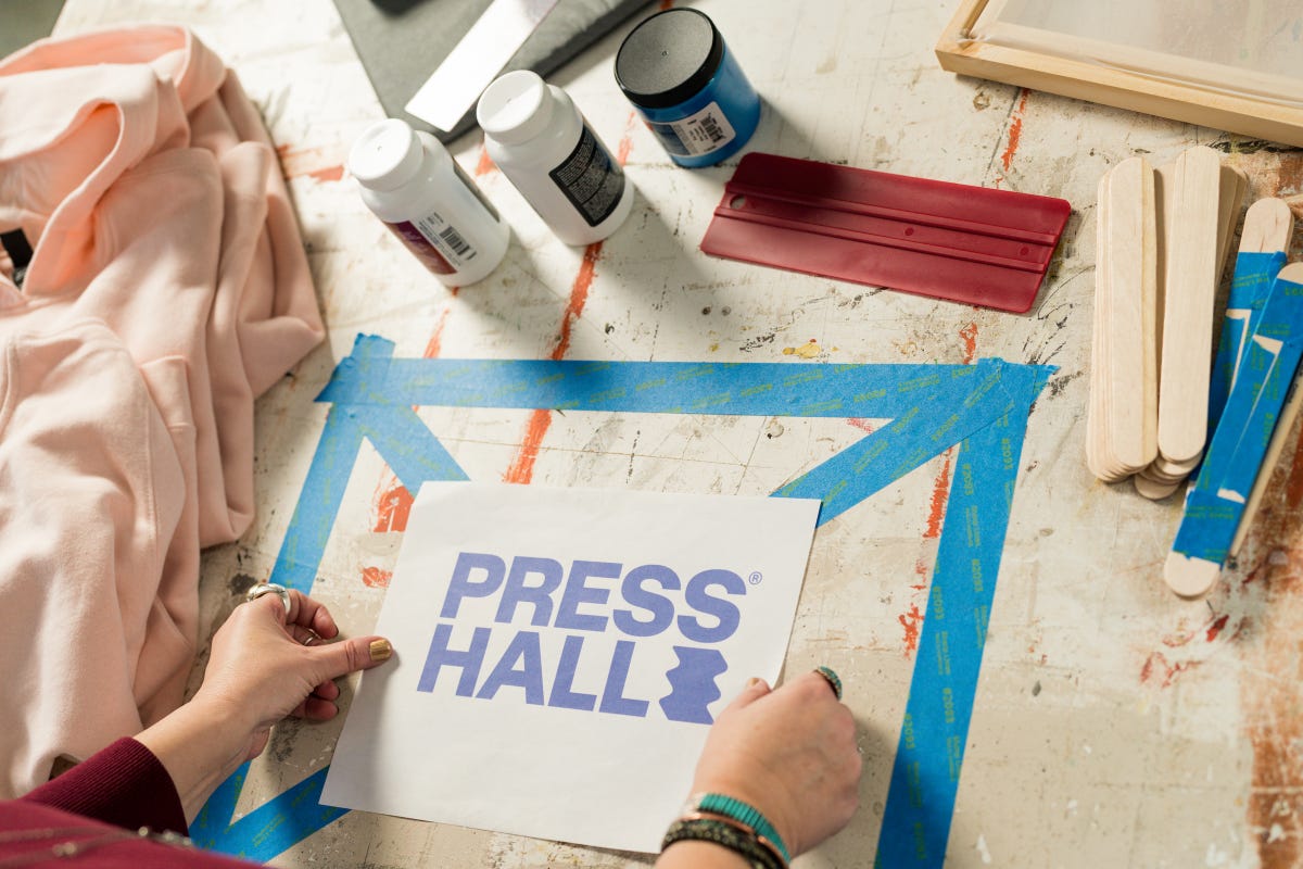 Printed design with the Press Hall logo placed on the center of the taped "X" surface.
