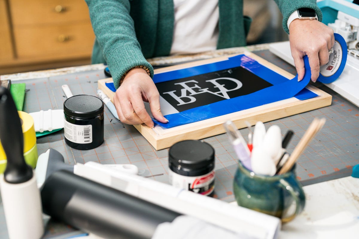 Vinyl side of the screen printing frame getting secured with painters tape.