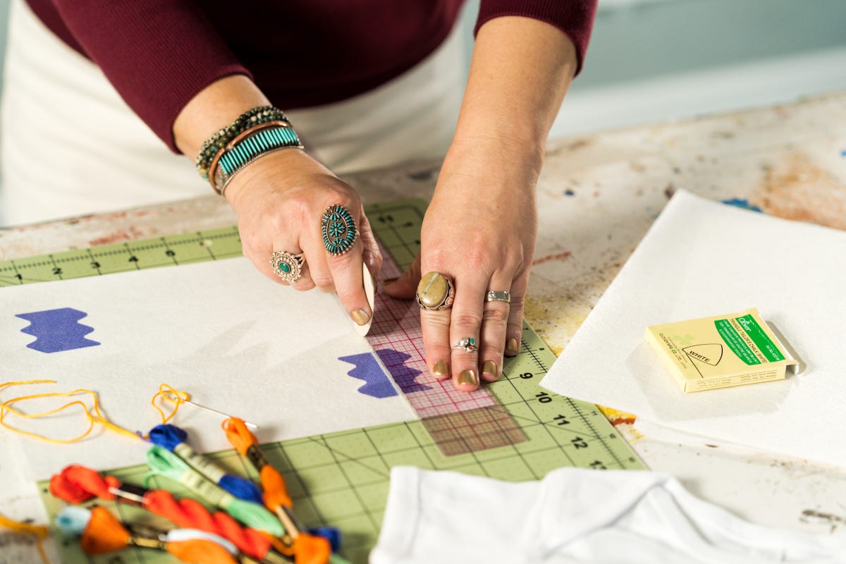Press Hall logo printed on an embroidery stabilizer being measured to find the middle point.