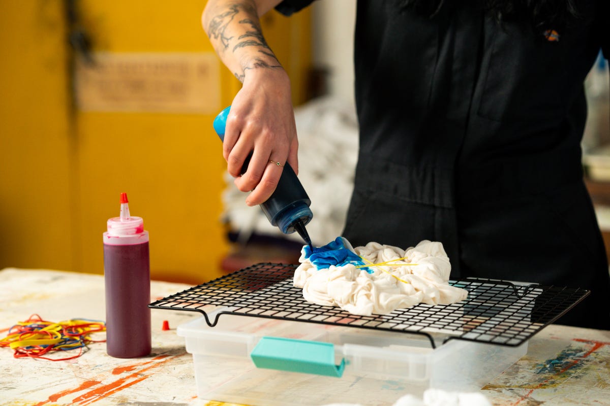 Blue dye being squeezed out of a bottle and onto a white t-shirt.