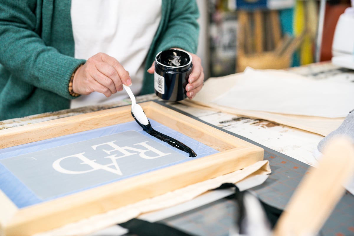 Ink scooped out with a spoon being spread across one side of the screen printing frame.