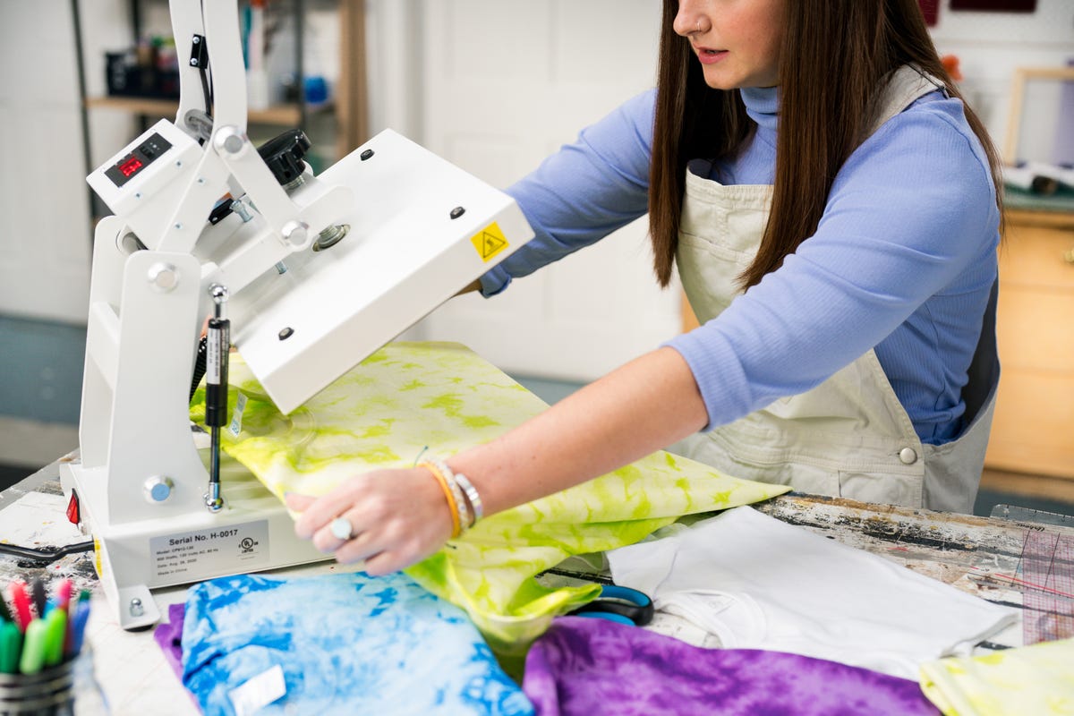 Allie placing the green crystal-dyed t-shirt on the heat press.