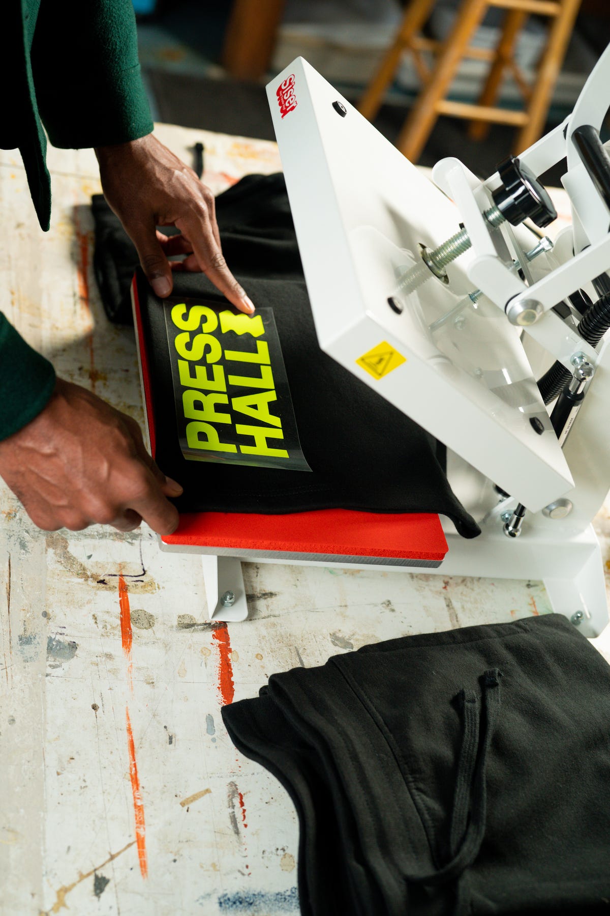 Black sweat shorts placed on a clamshell heat press with a fluorescent yellow heat transfer vinyl.