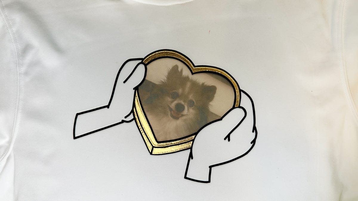 Black HTV outline of two hands holding a gold heart frame with a Pomeranian dog.