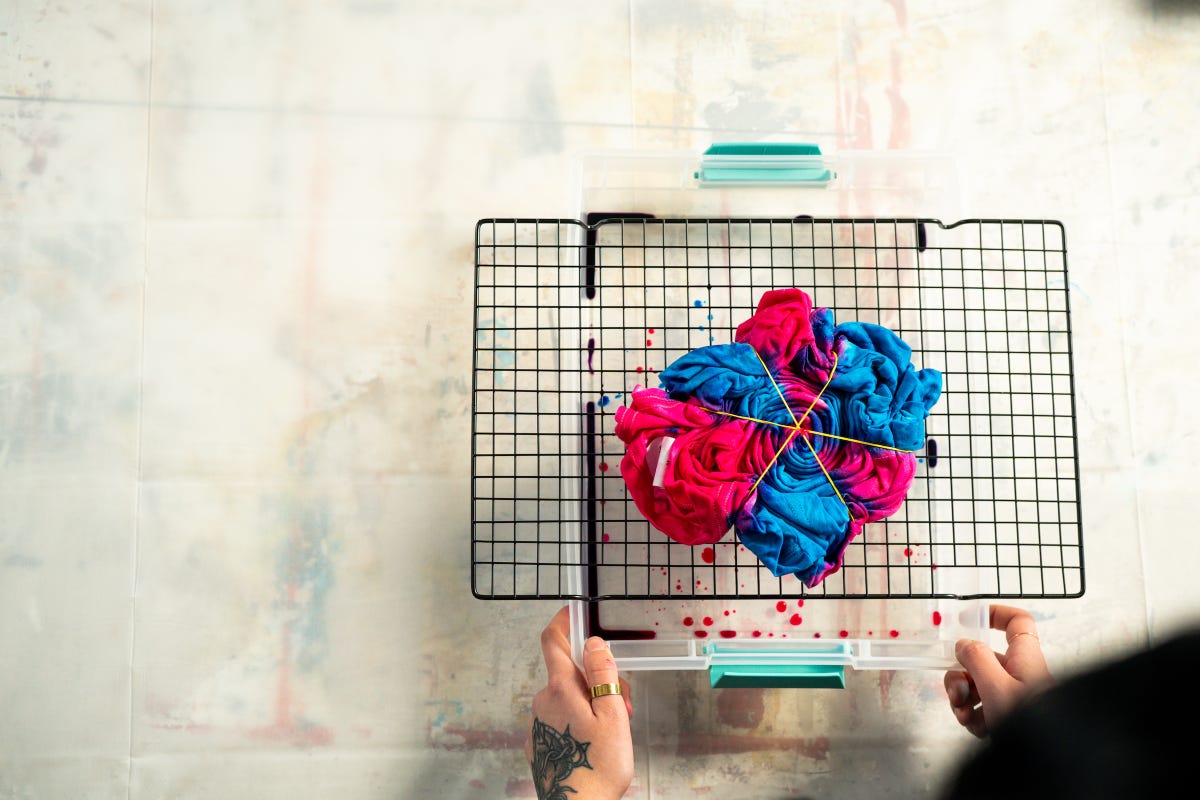 Blue and red tie-dyed t-shirt resting on the backing rack to cure the dye.
