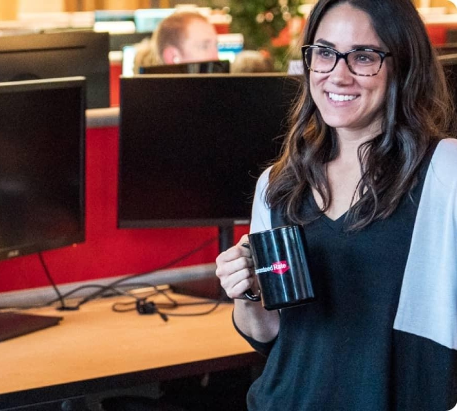 Woman smiles while holding a coffee mug.