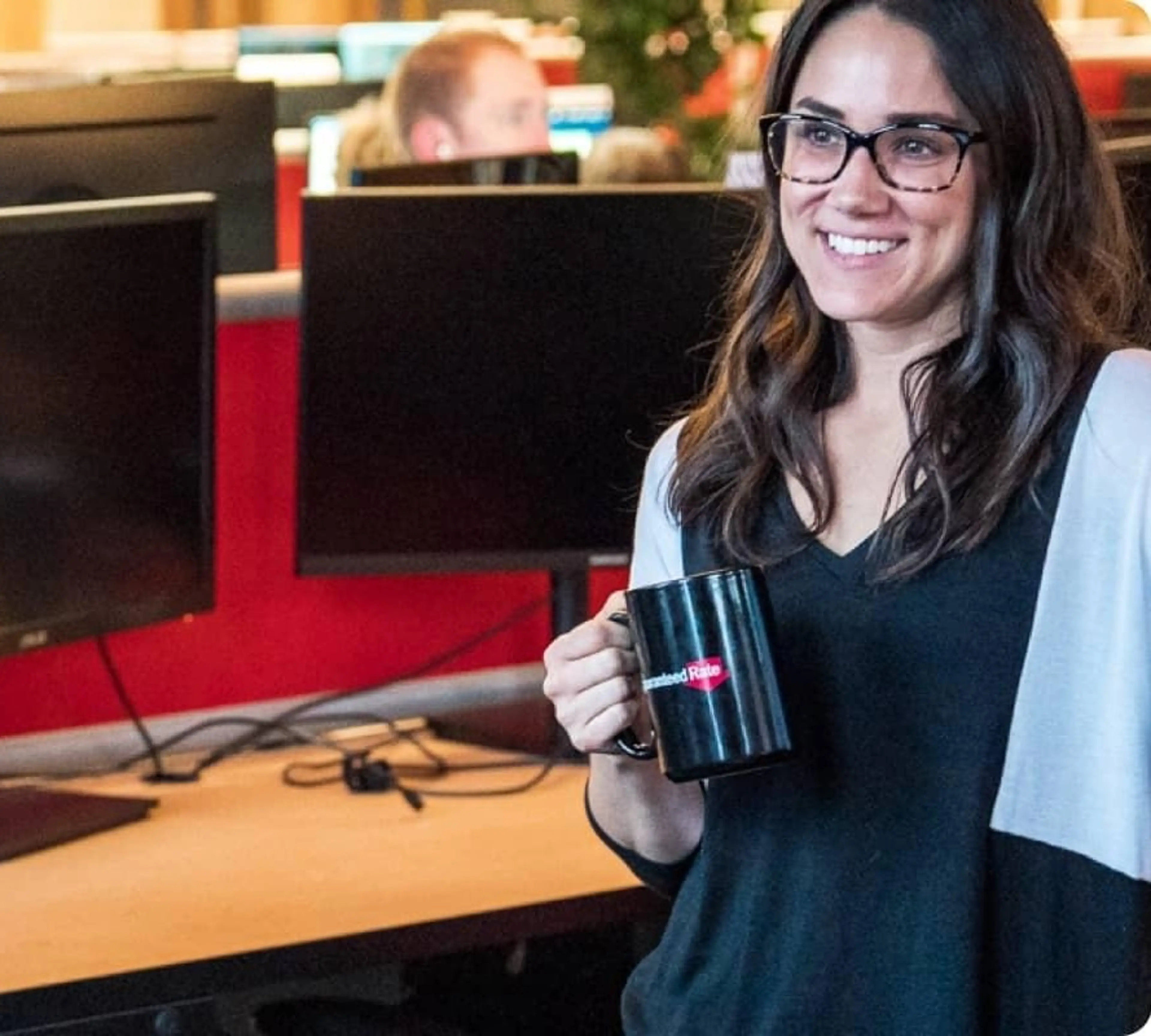 Woman smiles while holding a coffee mug.