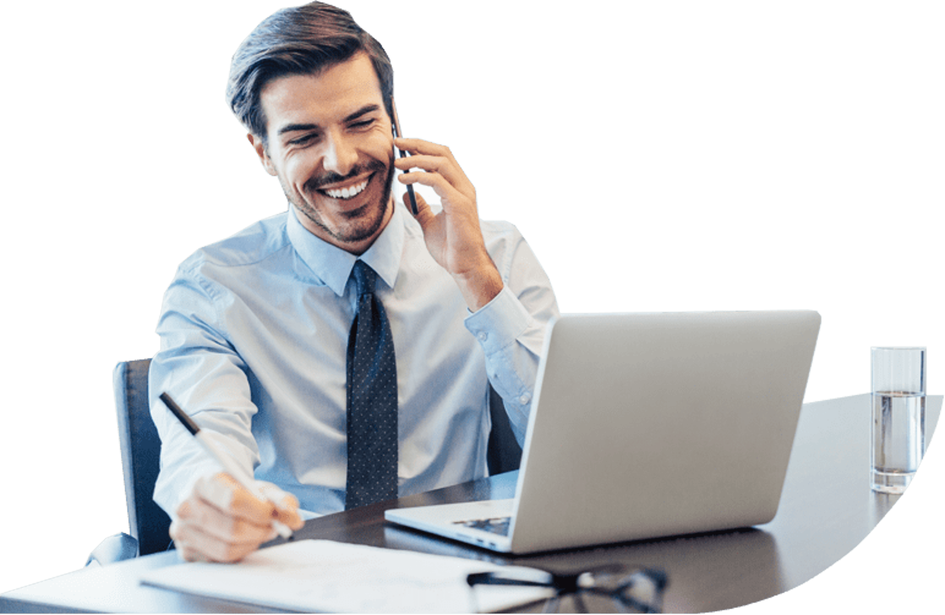 Person smiling while talking on the phone as they sit at a desk with their laptop.