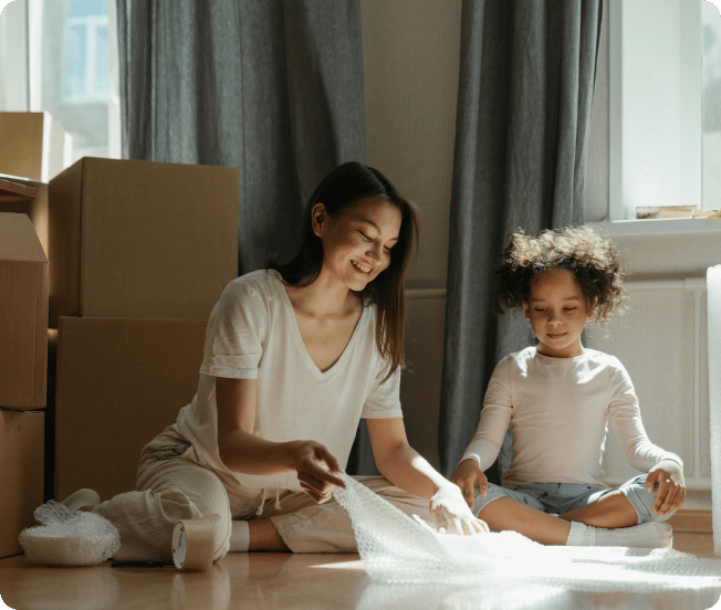 Woman and young girl packing items in bubble wrap