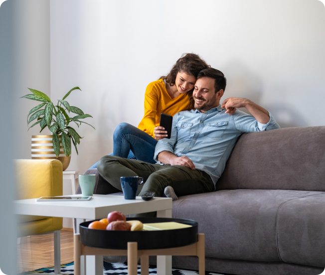 A man and a woman cuddling on a couch and smiling
