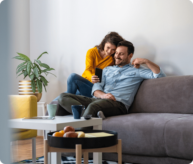 A man and a woman cuddling on a couch and smiling