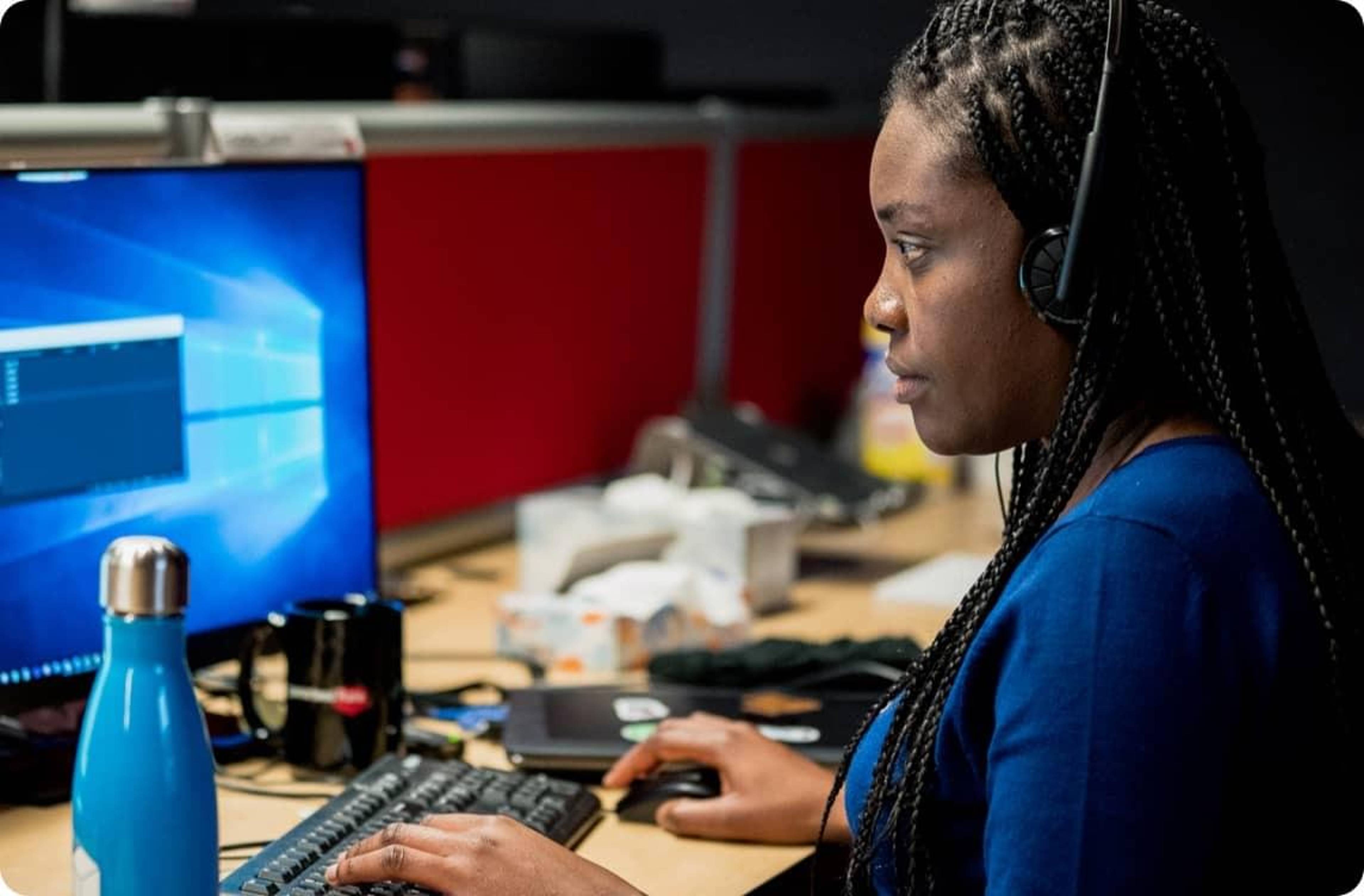 A Rate employee wearing a headset while working at their computer.