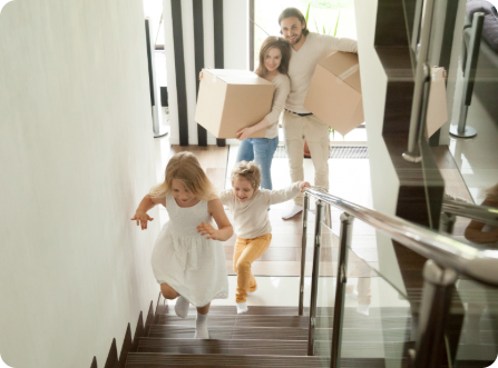 Family carrying boxes up the stairs in their new home