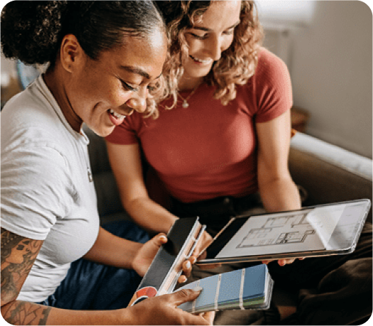 2 women on the couch looking at a tablet for paint samples