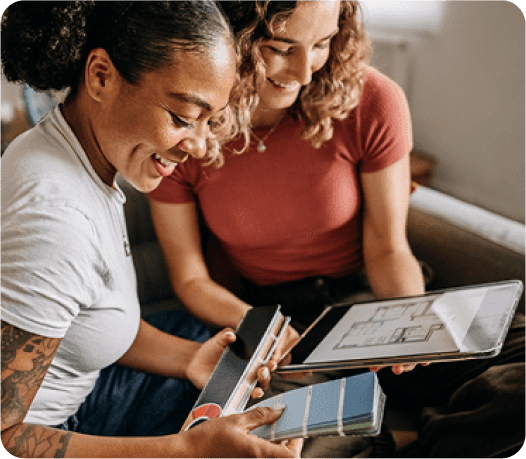 2 women on the couch looking at a tablet for paint samples