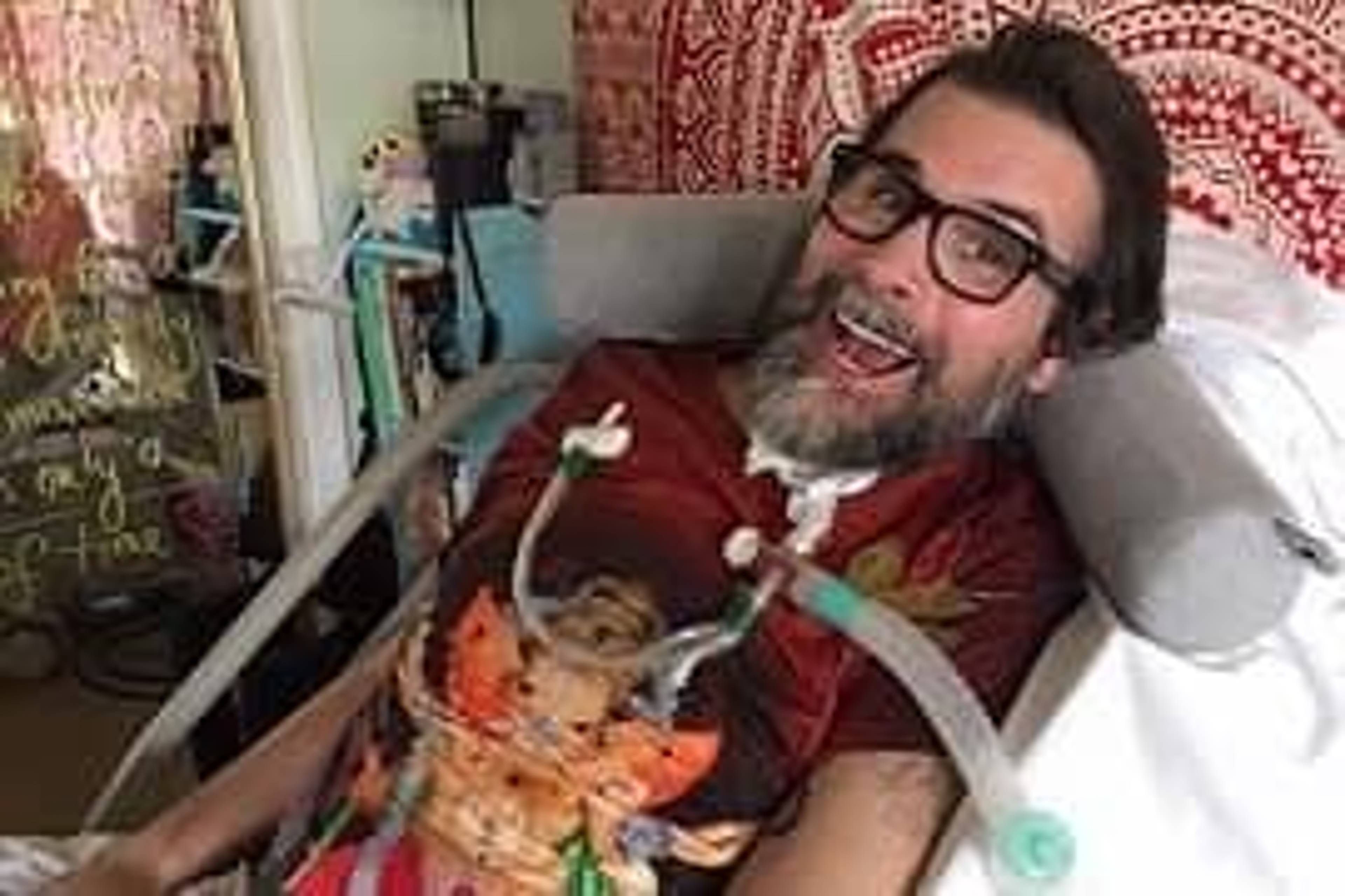 A man smiling while lying in a medical bed.