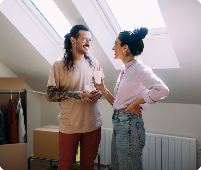 A man and a woman standing close and looking at each other with coffee cups