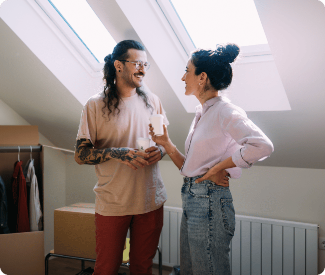 A man and a woman standing close and looking at each other with coffee cups