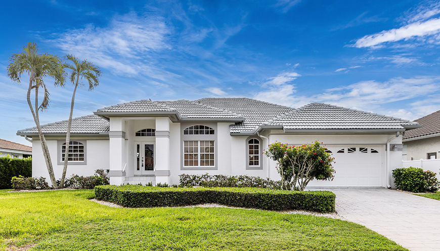 A single-story home with hedges and a lawn in front.