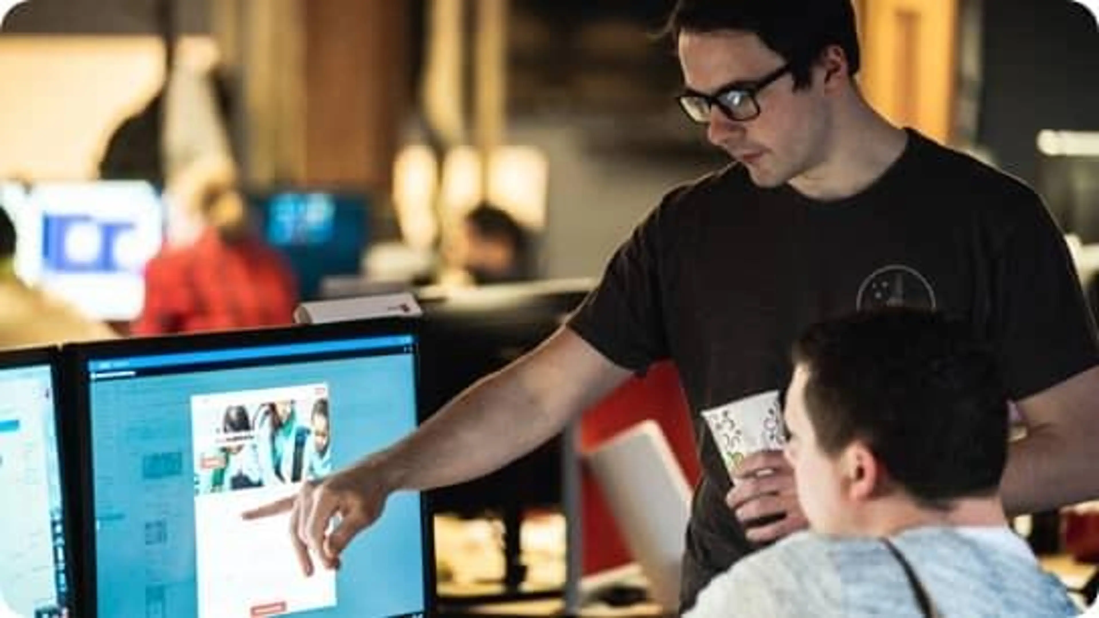 Two Rate employees point at a computer screen.