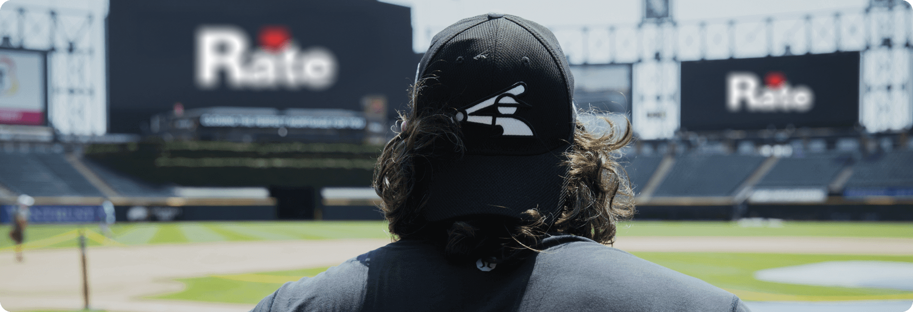 Baseball player looking at the stadium seats from the middle of the field with his back to the camera.