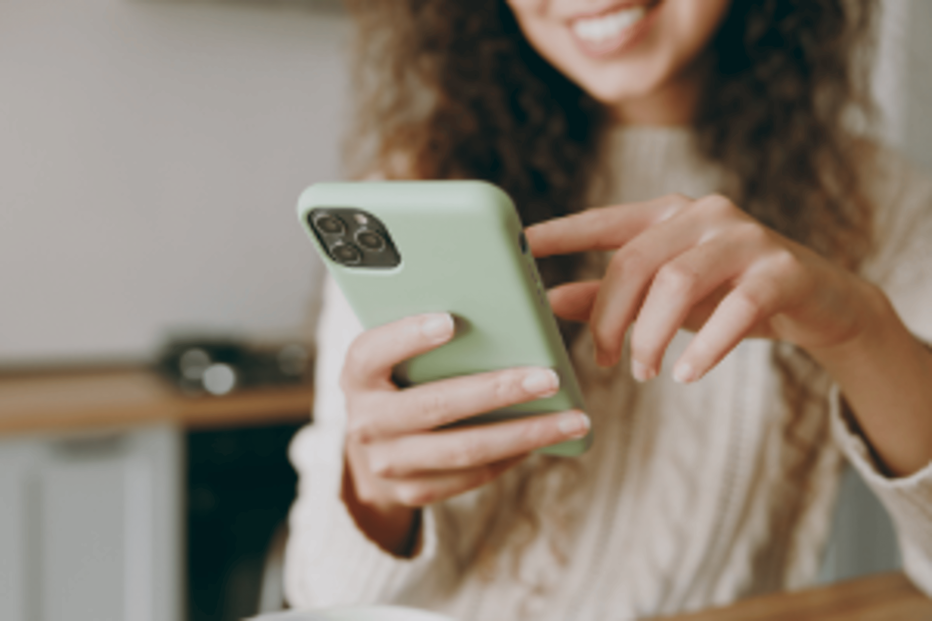 A woman tapping her phone screen while smiling.