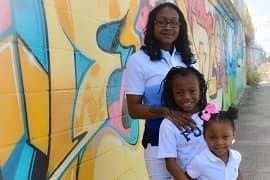 Two sisters smiling in front of a mural.