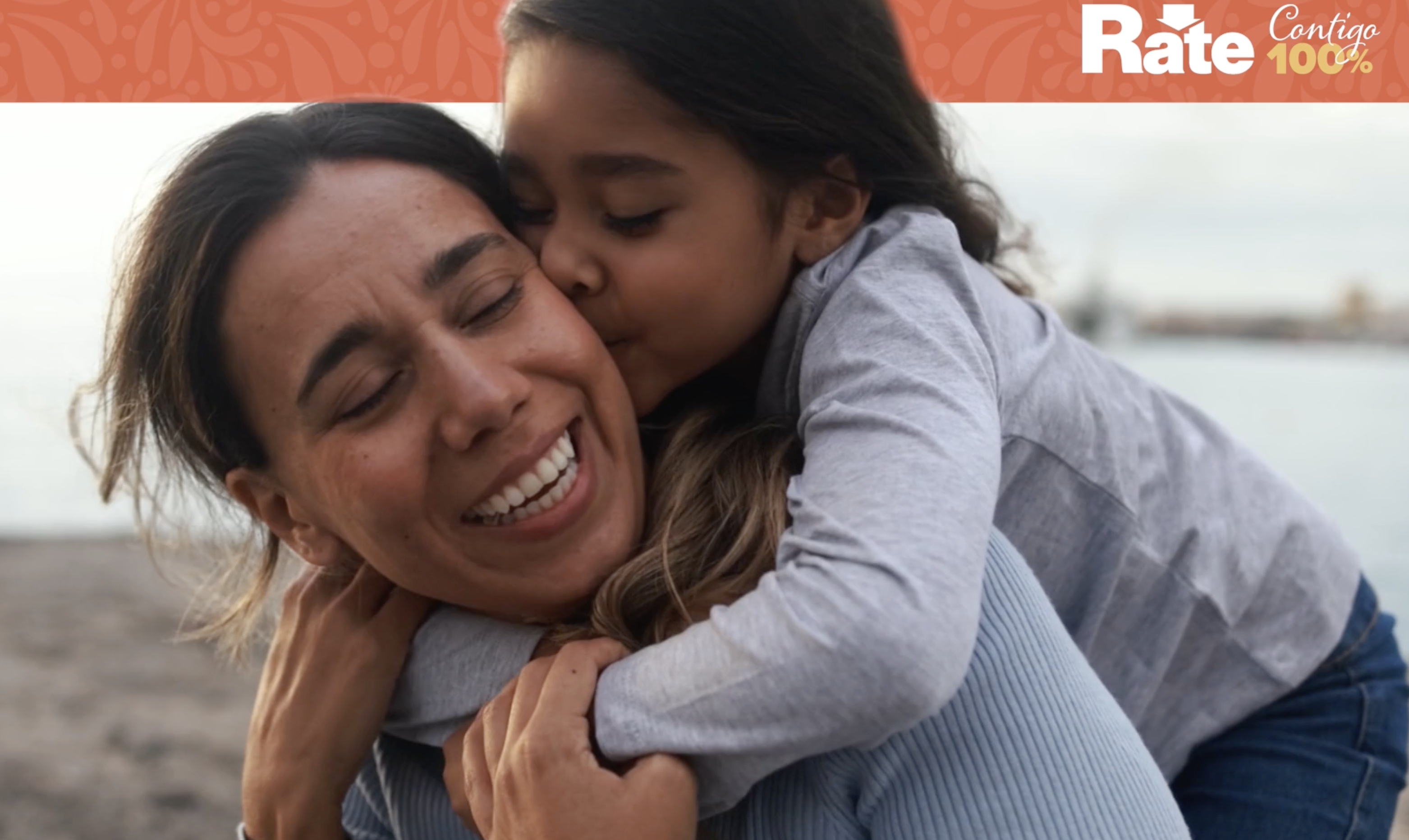 A child hugs her mother from behind.