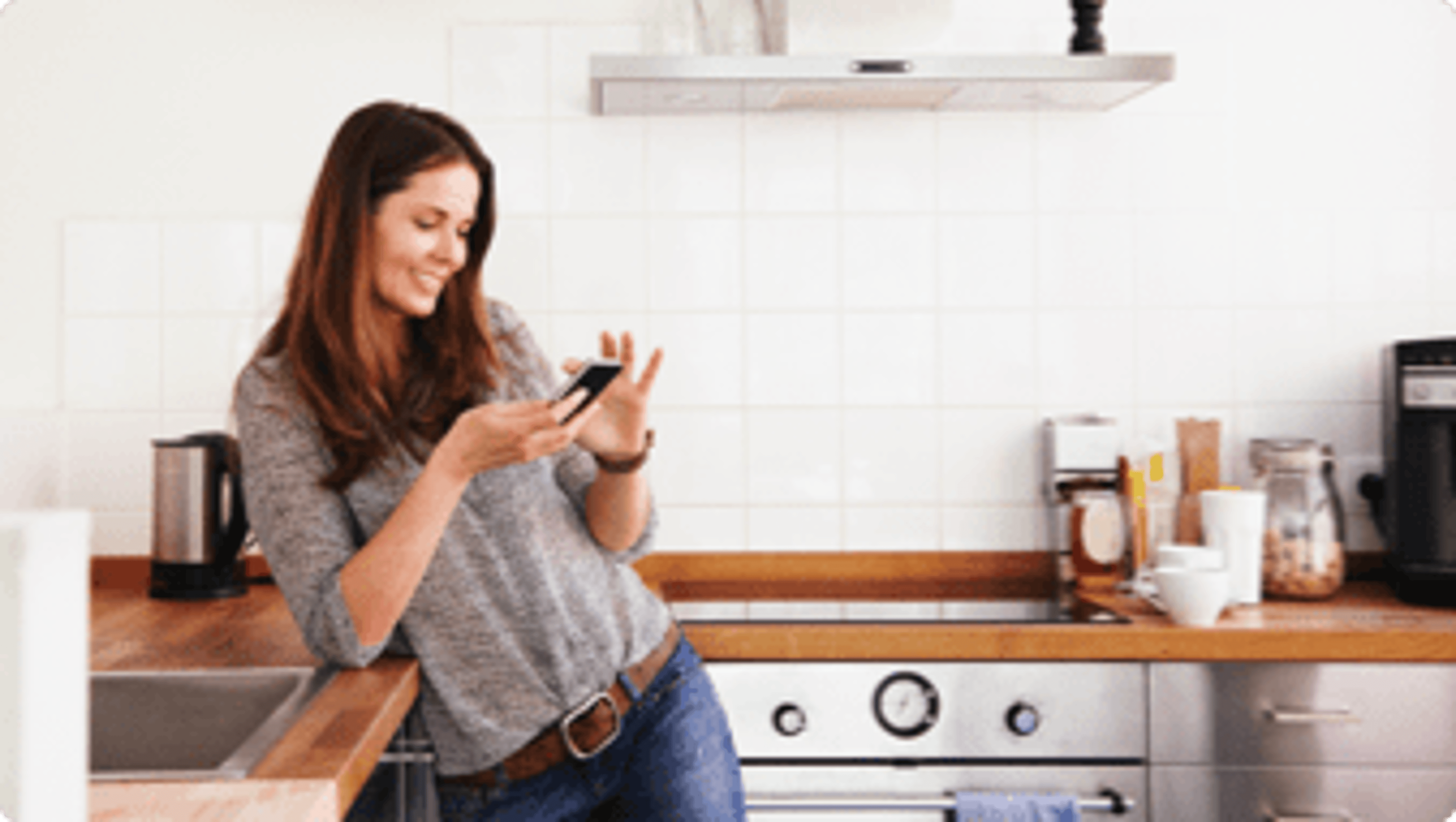 A woman in a kitchen looking at her phone