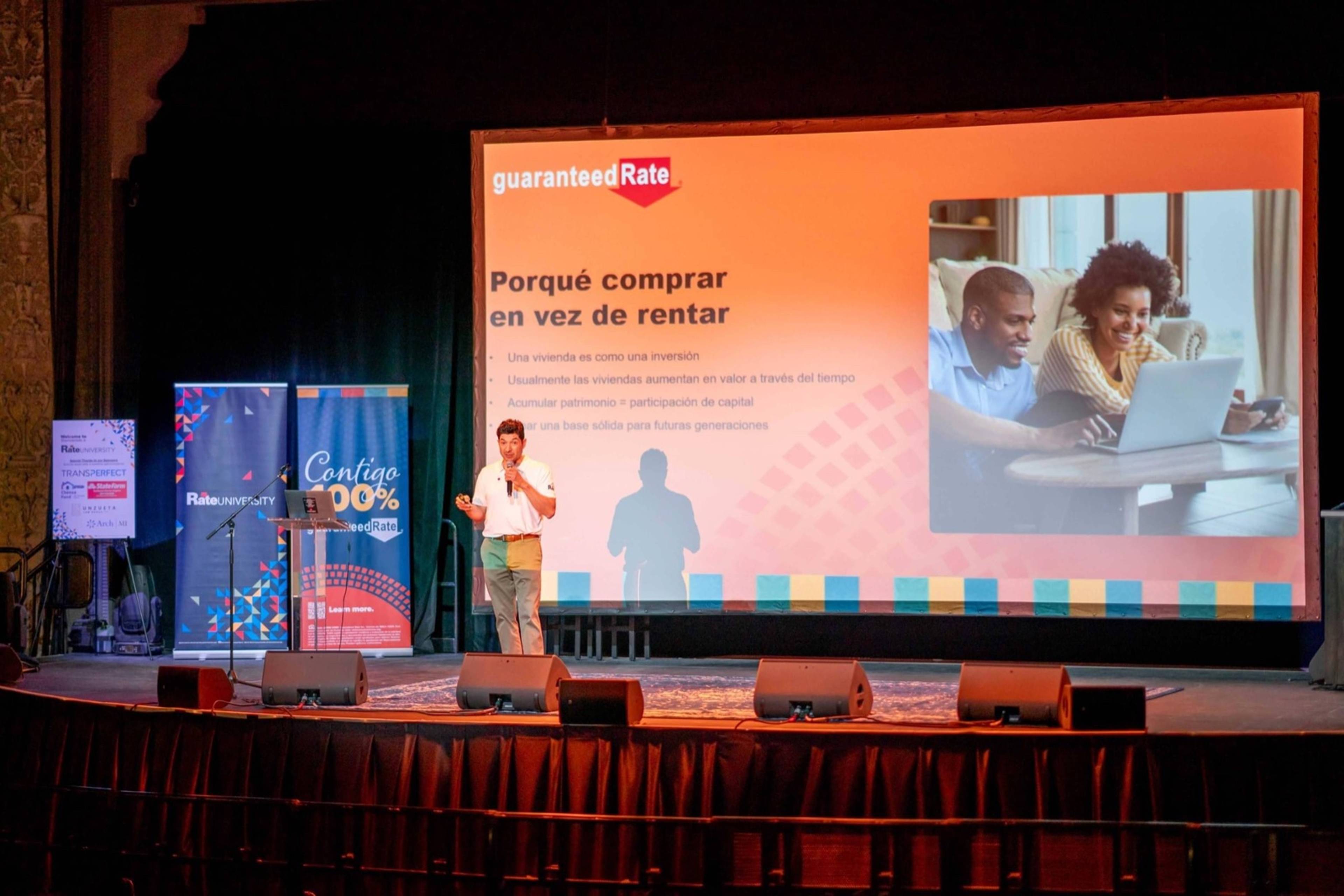 Speaker presenting a Spanish-language homebuying talk on stage.