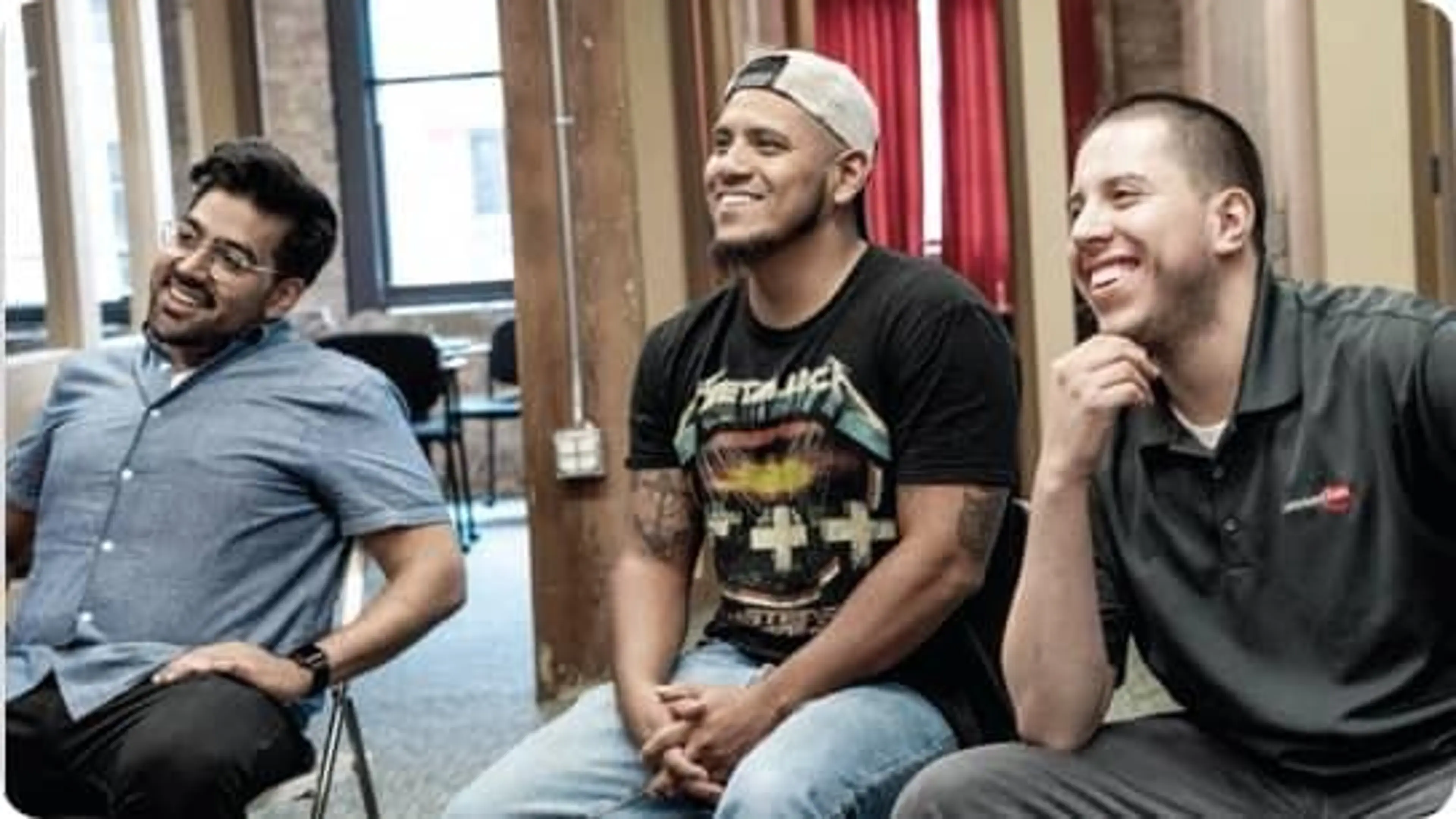 Three employees sit together smiling.