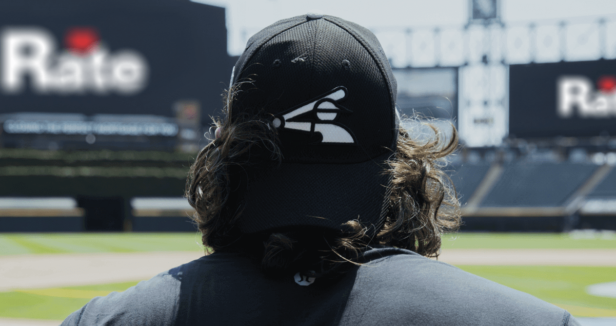 The back of the head and shoulders of a baseball player standing in a baseball field.